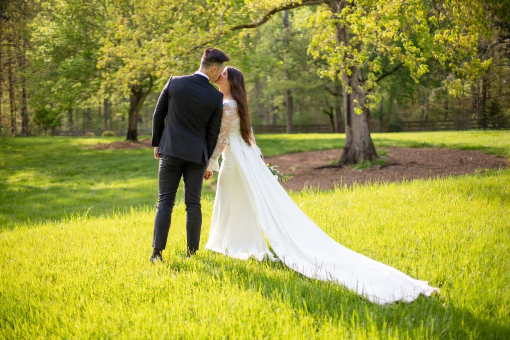 bride and grrom standing in a field kissing during their wedding day
