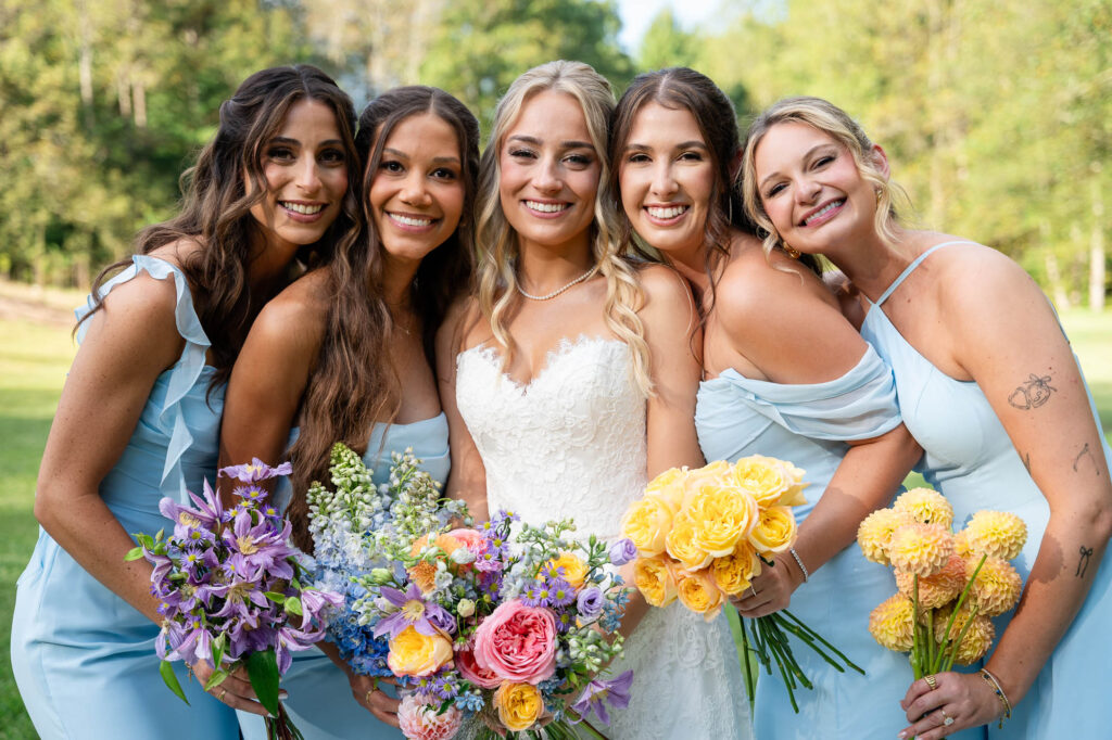 Bridesmaids in soft blue dresses smiling with the bride at a Georgia vineyard wedding