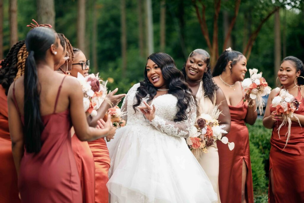 Bridesmaids in rust-colored dresses share joyful moments with the bride at the Castle at Wildwood Gardens