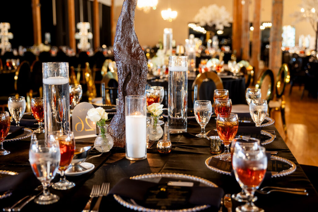 Elegant wedding reception table with black linens, crystal glassware and lit candles creating romantic ambiance at Bibb Mill Event Center