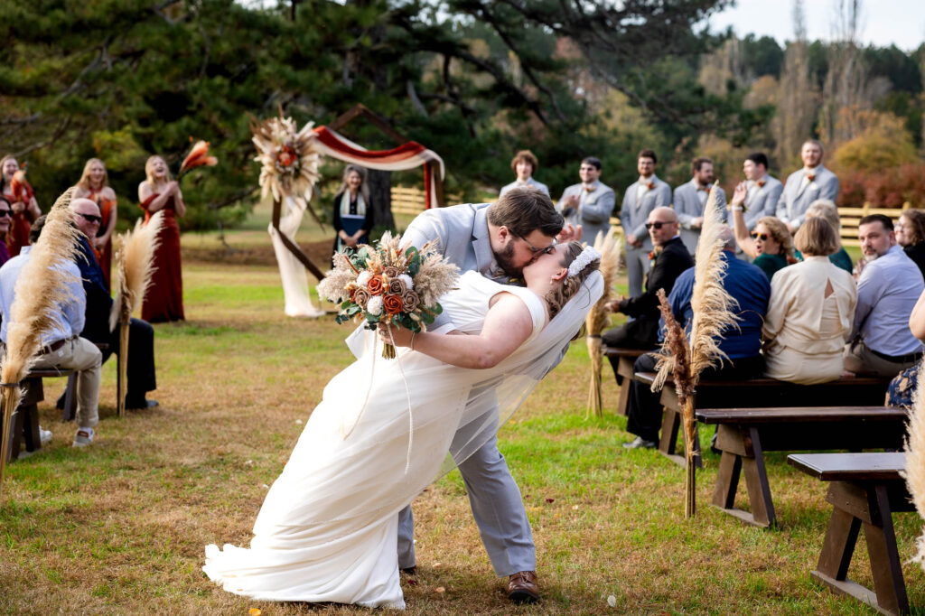 bride and groom dip and kiss after wedding ceremony