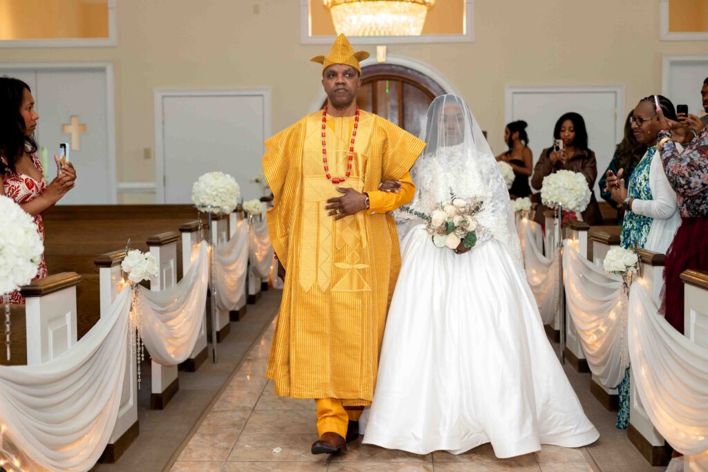 father dressed in african attire walking his daughter down the aisle at a wedding at Pristine chapel in Atlanta 